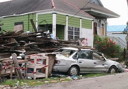 outside of a home destroyed by the hurricane, a car covered in rubble