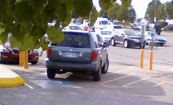 a car parked next to the yellow curb and across both the parking space and the access aisle