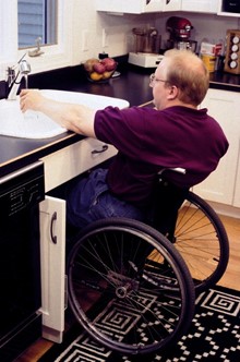 a wheelchair user getting a glass of water from his modified sink